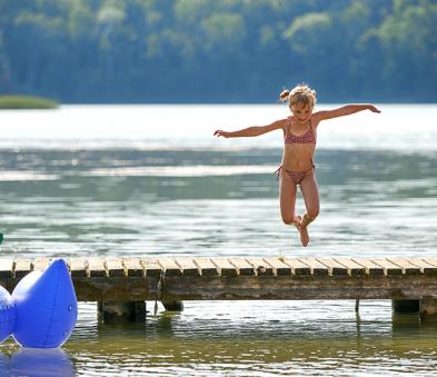Dziewczynka skacząca do wody z pomostu